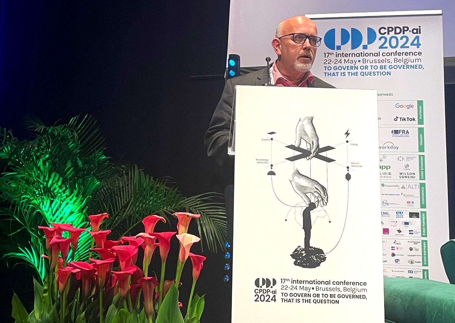 The European Data Protection Supervisor delivering a speech at CPDP conferences behind a podium and next to plants and flowers